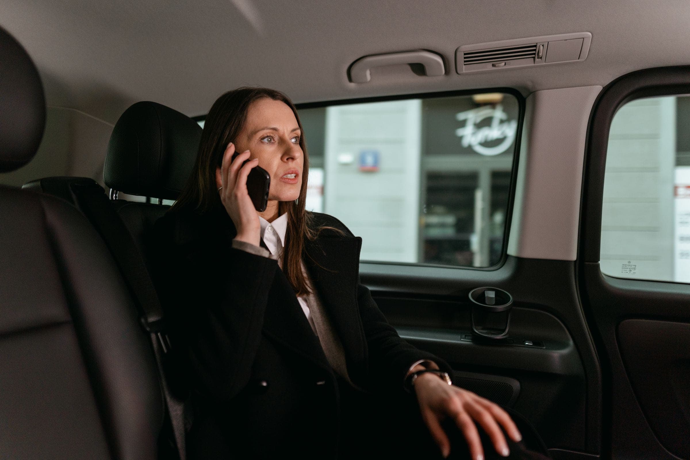 Passagère installée à l'arrière d'une berline conduite par un chauffeur