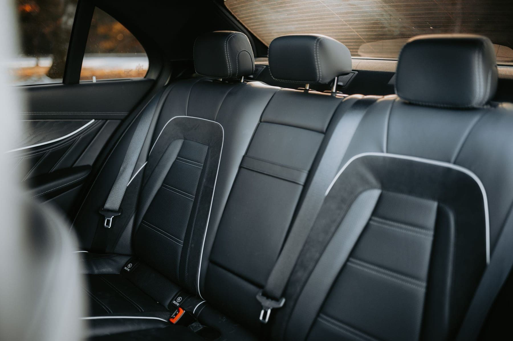 Black leather rear seats of a saloon, lit by daylight