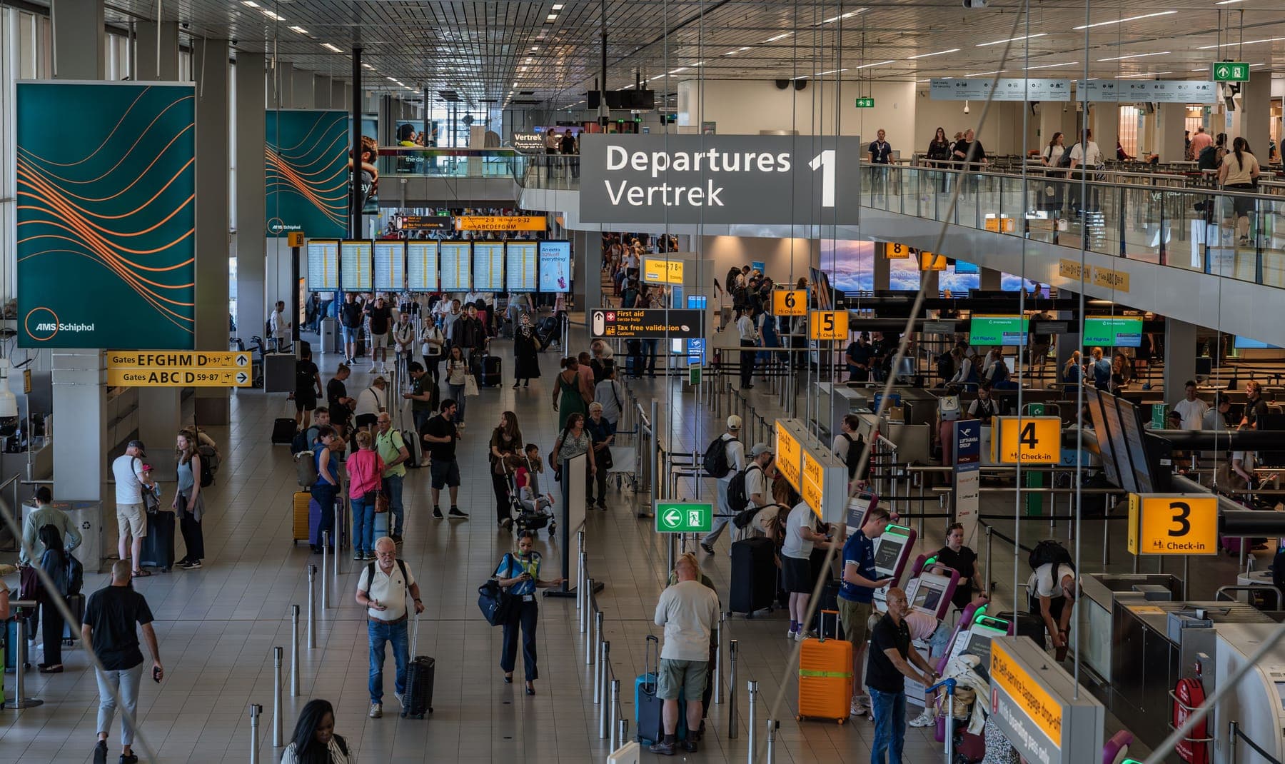 Airport departures hall, with the Departures / Vertrek sign above the check-in desks