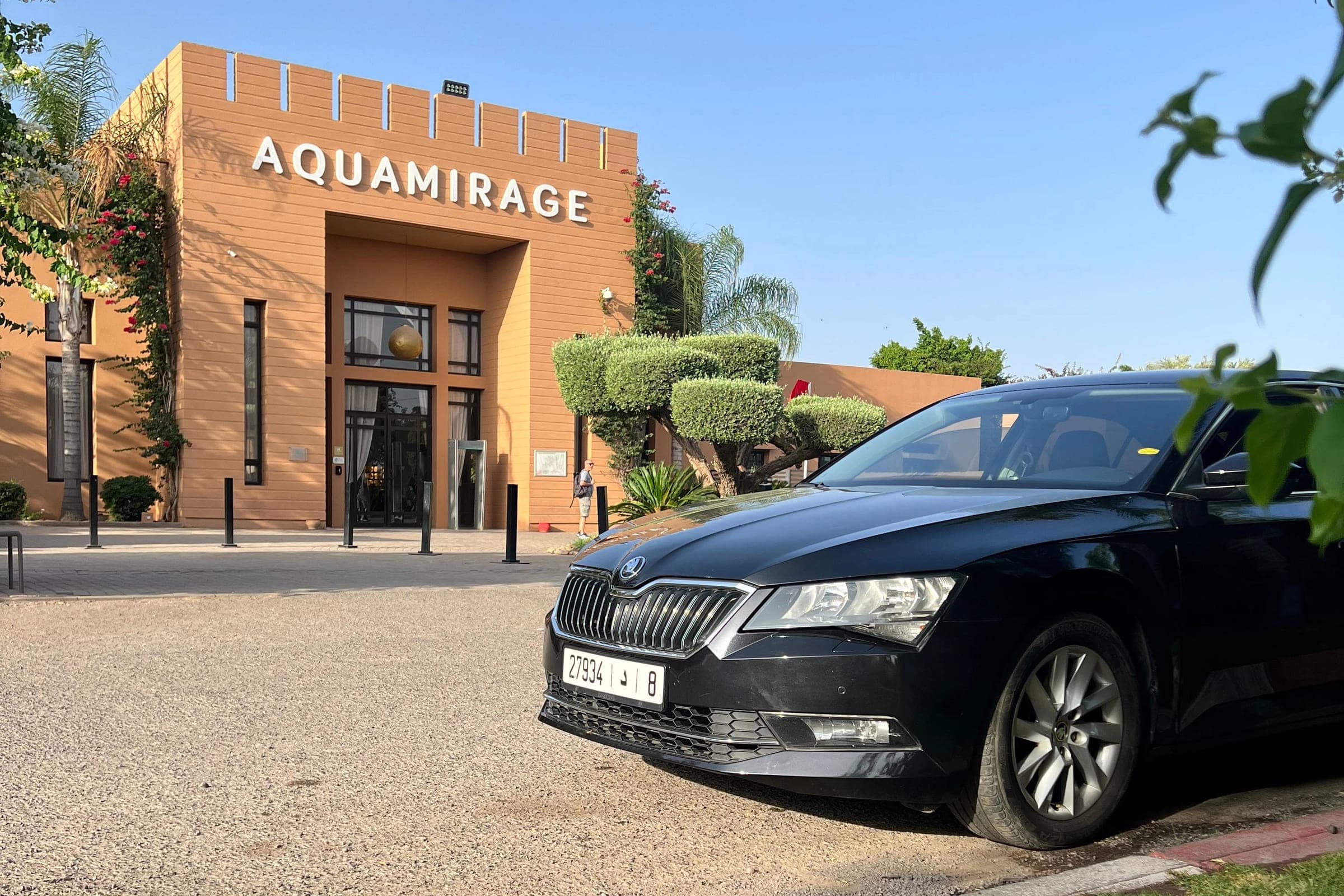 Škoda Superb noire à l'arrêt devant l'entrée d'un hôtel, sous un ciel dégagé