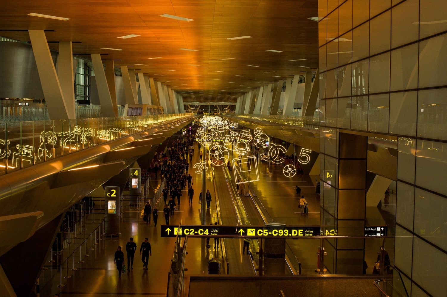 Hall d'aérogare moderne baigné d'une lumière chaude, vue vers les portes d'embarquement